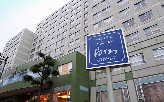 新潟県湯沢にある「ホテル シャーレゆざわ 銀水」の建物外観と、青地に白文字で書かれた大きな看板。