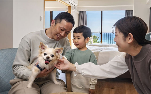 静岡県の愛犬と泊まれる宿「熱川オーシャンリゾート」のオーシャンビュー客室で、愛犬のチワワを囲んで笑顔で過ごす家族